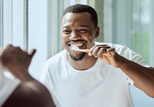 Man smiling while brushing his teeth