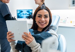 Patient smiling while holding mirror in treatment chair