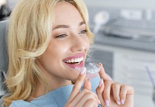 Patient smiling while holding clear aligner