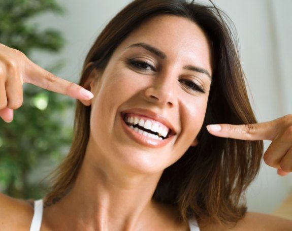 Woman pointing to smile after teeth whitening