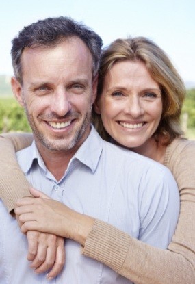 Man and woman smiling after dental implant tooth replacement