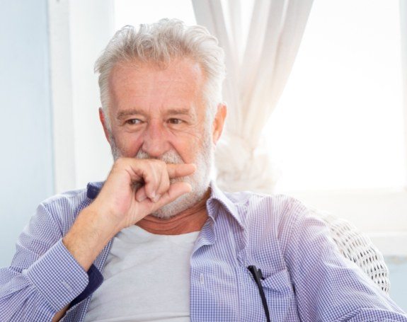 Man in need of dental implant tooth replacement covering his mouth