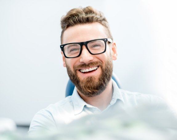 Man smiling after understanding the cost of tooth replacement with dental implants