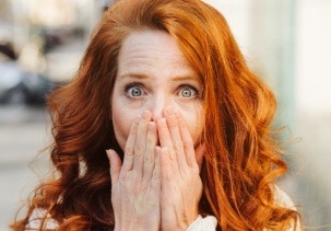 Woman with knocked out tooth covering her mouth