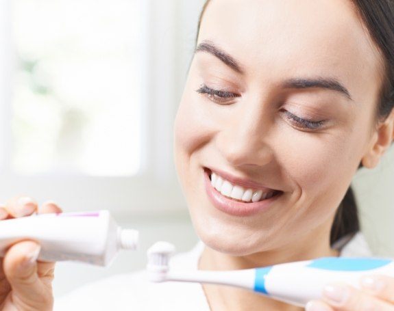 Woman brushing teeth to prevent dental emergencies