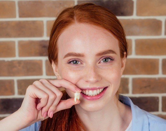 Woman holding up her tooth after extraction