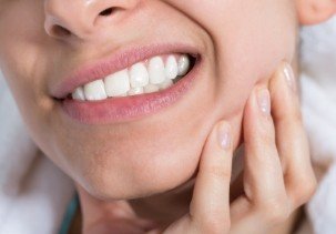 Woman with toothache holding jaw in pain