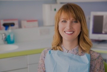 Woman in dental chair smiling after preventive dentistry
