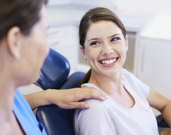 Woman smiling at dentist during dental checkup and teeth cleaning visit