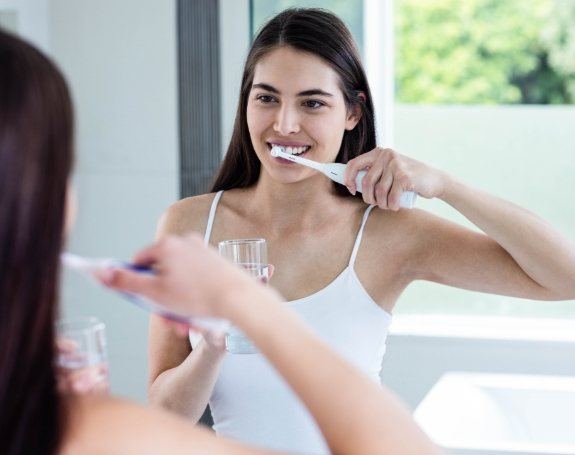 Woman using at home dental hygiene products to care for her smile