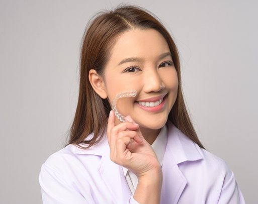 Smiling patient holding clear aligner