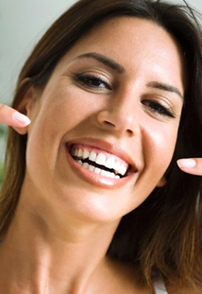 Woman smiling and pointing to veneers in Chardon