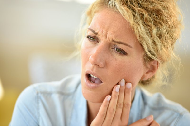 Person holding their cheek in pain