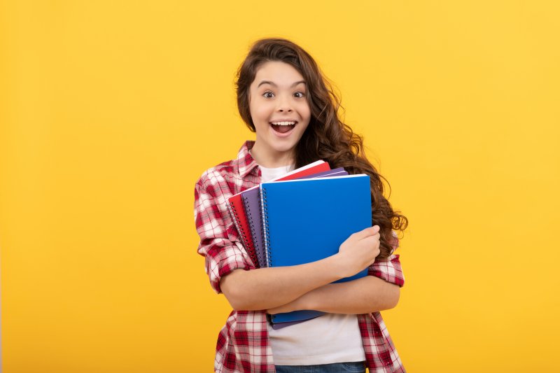 Smiling teen holds books.