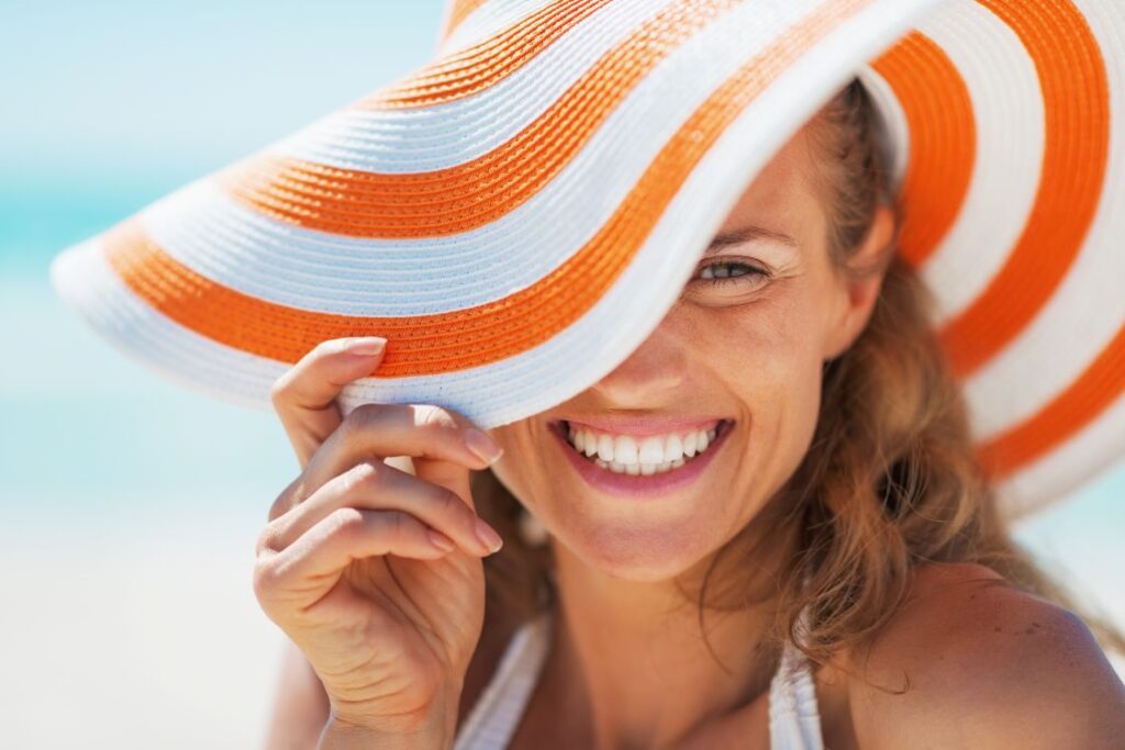 A smiling woman wearing a sun hat on the beach